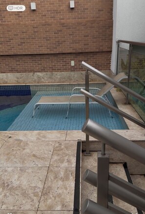 A swimming pool with a tiled deck and metal railings.
