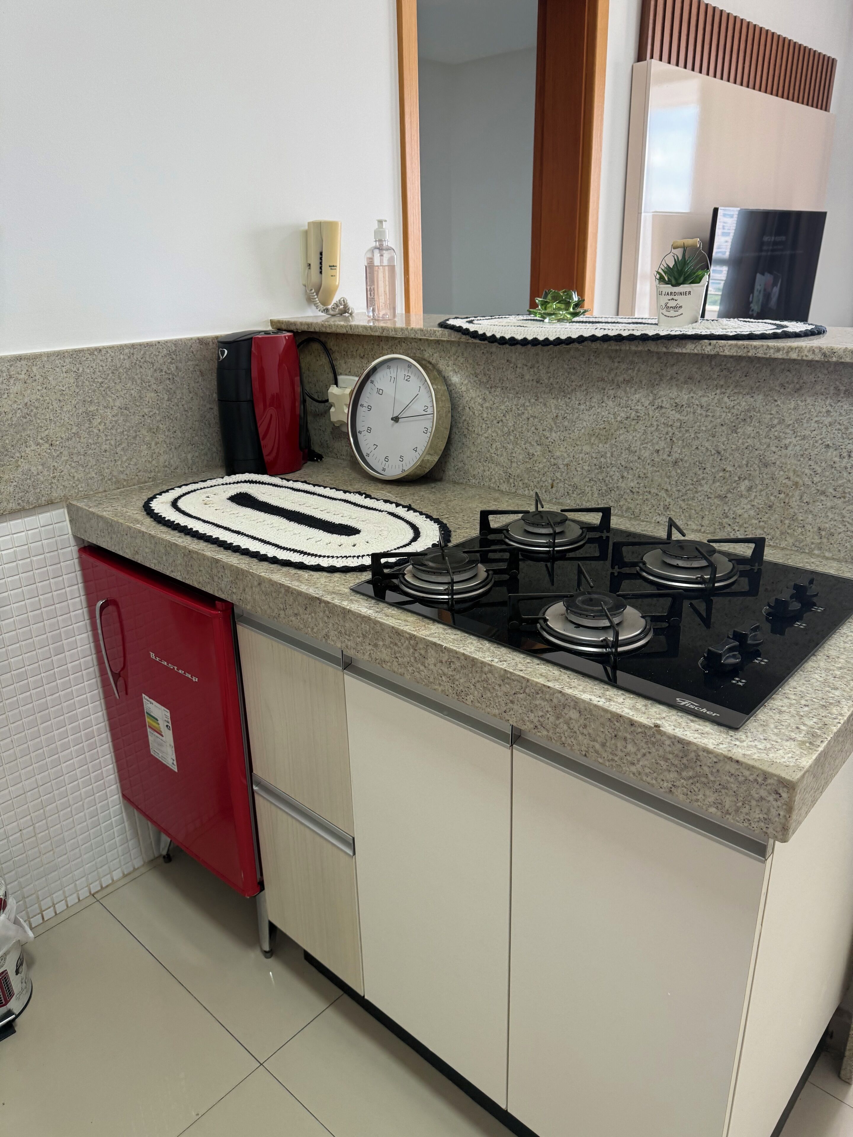 A kitchen with a gas stove, a clock, and a red appliance.
