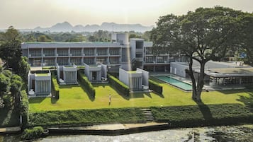 A modern building with a pool, surrounded by well-maintained lawns and a body of water.