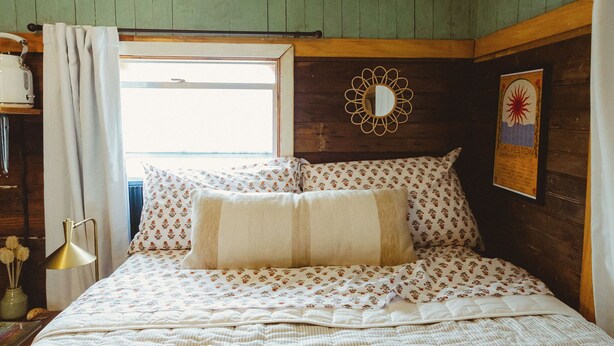 A bedroom with a bed, a window, a mirror, and a wall decoration. - Cozy Rustic Sailors Room (Houston)