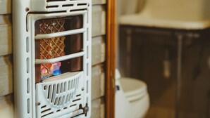 A bathroom with a white toilet, a white sink, and a white heater mounted on the wall. - Cozy Rustic Sailors Room (Houston)