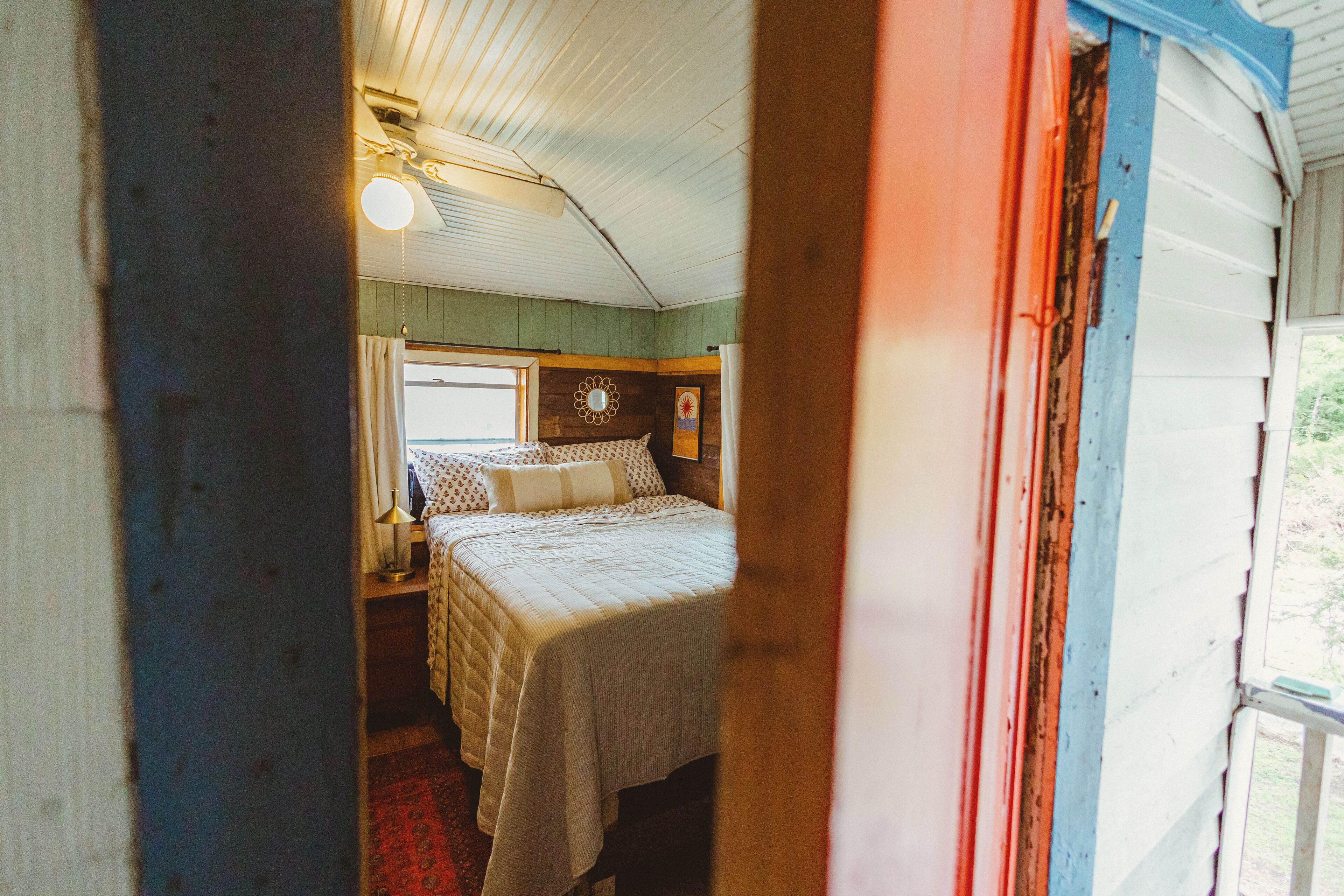 A bedroom with a bed, a nightstand, a lamp, and a window.