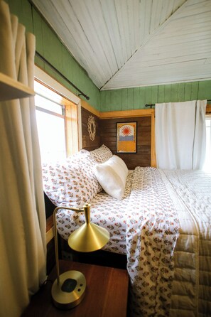 A cozy room with a bed, a lamp, and a framed picture on the wall. - Cozy Rustic Sailors Room (Houston)
