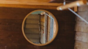 A circular mirror reflecting a stack of books, a wooden shelf, and a white cabinet. - Cozy Rustic Sailors Room (Houston)