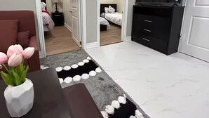 Een moderne slaapkamer met een bed, een televisie en een bureau met een bloevas.
