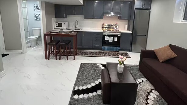 Een moderne keuken met donkere kastjes, een roestvrijstalen koelkast en een magnetron.