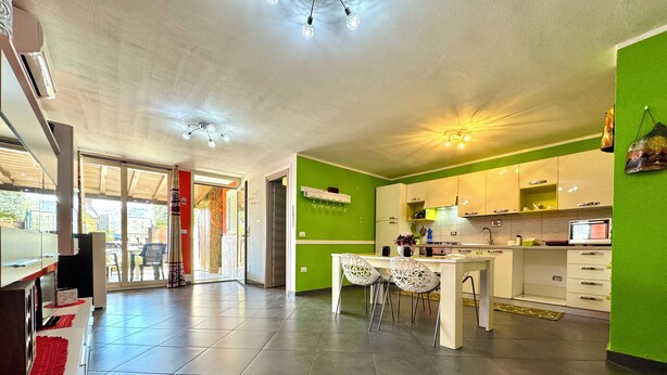 A spacious kitchen with a dining area, a large island, and a view through a glass door to an outdoor patio. - "  Happy  Apartment " (Bari Sardo)