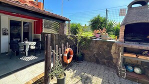 A patio with a stone wall, a barbecue grill, and potted plants. - "  Happy  Apartment " (Bari Sardo)