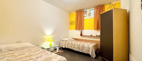 Une chambre avec deux lits, une petite table avec une lampe, une armoire et une fenêtre avec des rideaux.