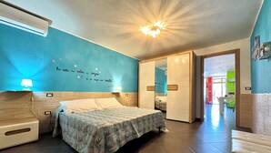 A bedroom with a bed, bedside tables, a wall with a quote, and a ceiling light. - "  Happy  Apartment " (Bari Sardo)