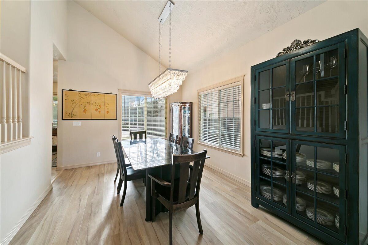 A dining room with a large table, chairs, a chandelier, and a cabinet with glass doors.