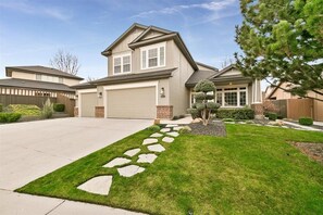 A two-story house with a garage, a well-maintained lawn, and a stone pathway leading to the entrance. - Luxury 3 BD/3BA house in charming Boise with WiFi, AC, Bikes, Com. Pool (Boise)