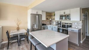 Een moderne keuken met witte kasten, roestvrijstalen apparatuur en een marmeren eiland.