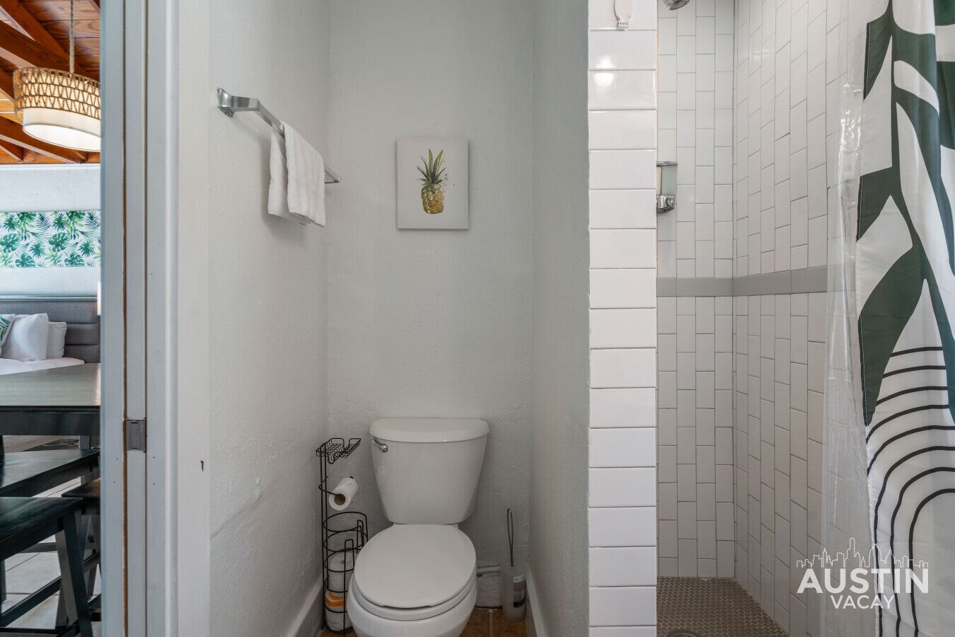 Een badkamer met toilet, een handdoekhouder en een douchegedeelte met witte tegels.