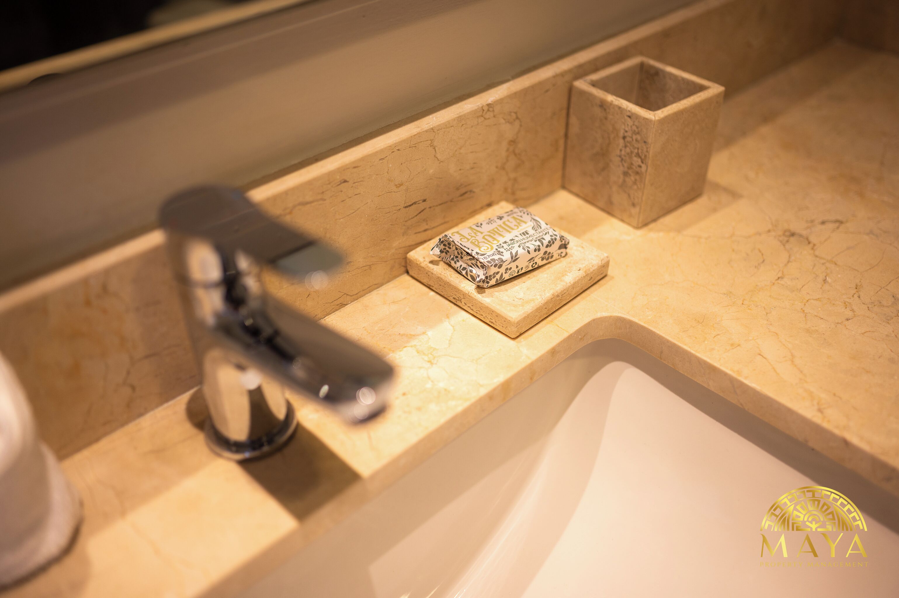 A bathroom sink with a marble countertop, a small soap dish, and a faucet.