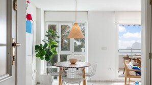 A modern dining area with a round table, white chairs, and a hanging light fixture. - Panorama by Interhome (Altea)