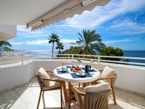A round table with chairs on a balcony overlooking the sea, with palm trees and a clear sky in the background. - Panorama by Interhome (Altea)
