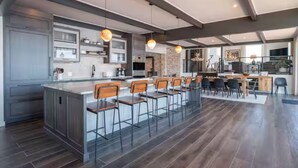 Une cuisine moderne dotée d’un îlot central, de tabourets de bar et de luminaires suspendus.
