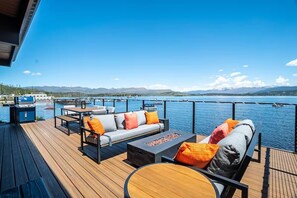 Une terrasse avec coin salon extérieur, un barbecue et une vue sur un lac et des montagnes.