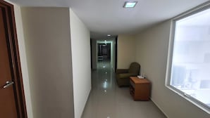 A hallway with a door on the left, a small table with a device on the right, and a window on the far right. - Hotel O De Melor Bangi Gateway (Bandar Baru Bangi)