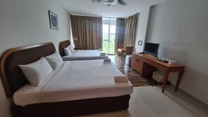 A hotel room with two beds, a desk with a television, and a view of the outdoors.