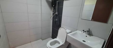 A small bathroom with a toilet, sink, and shower.
