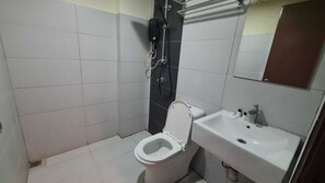 A small bathroom with a toilet, sink, and shower.