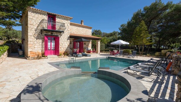 Un edificio de piedra con piscina y zona de estar al aire libre.