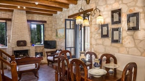 A cozy dining area with stone walls, wooden furniture, and a fireplace. - Villa Nephos - Beautiful sea views (Koiliomenos)