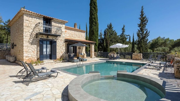 A stone house with a swimming pool, outdoor seating, and a tall tree in the background. - Villa Nephos - Beautiful sea views (Koiliomenos)
