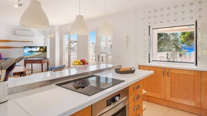 A modern kitchen with a central island, pendant lights, and a view of the outdoors.