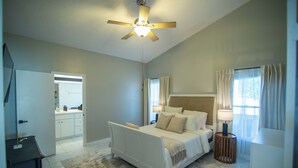 Un dormitorio con cama, mesita de noche, lámpara y ventilador de techo.
