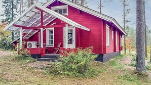 Een rode houten woning met schuin dak en een overdekte veranda.
