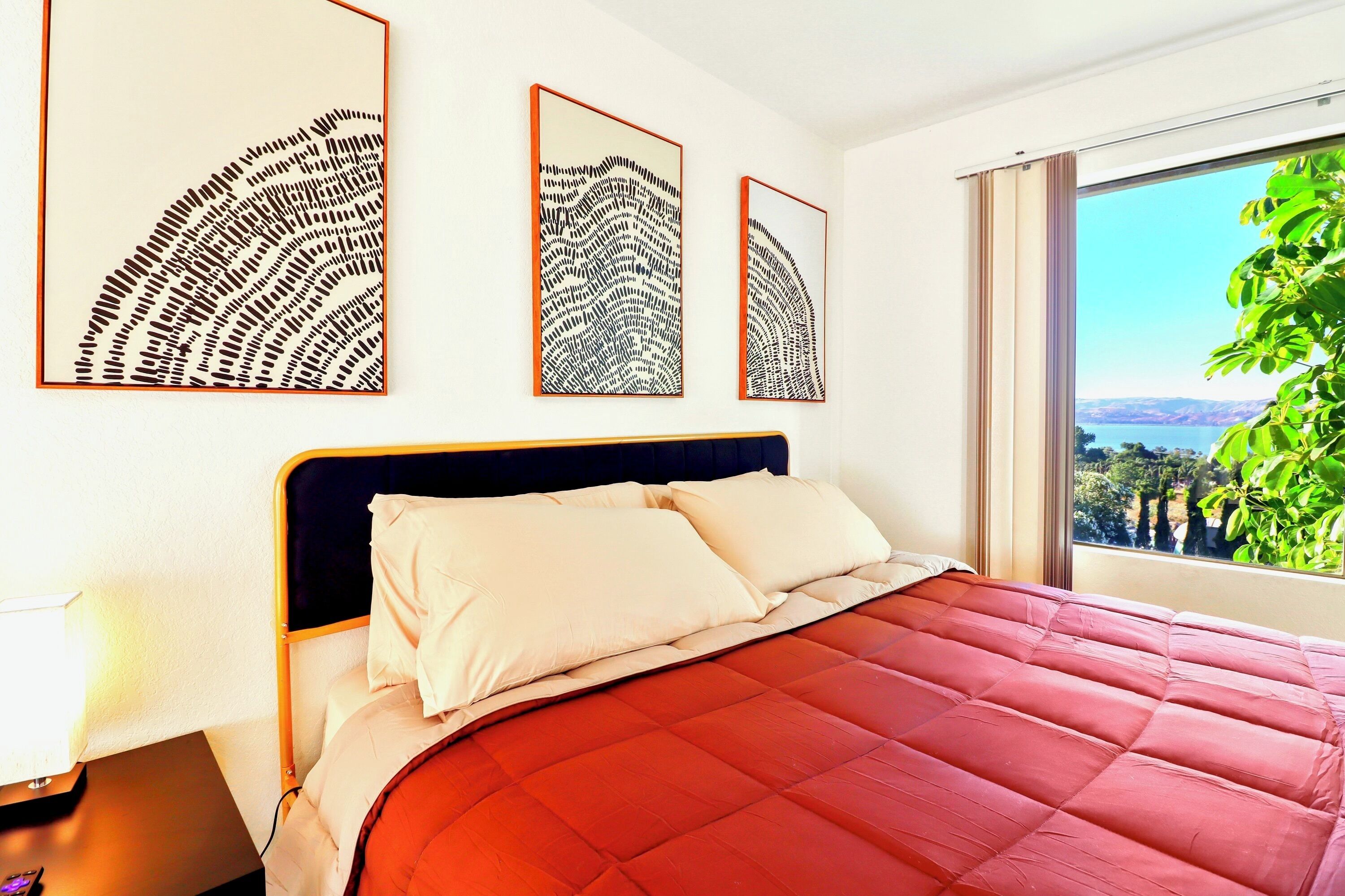 A bedroom with a large bed, a nightstand, and three wall-mounted artworks.