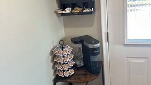 Un área de cafetería con una máquina de café, un portavasos y un letrero que dice "Coffee Bar".