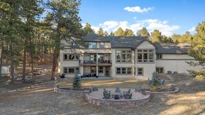 A two-story building with a covered patio and outdoor seating area. - Private Luxury Lodge in Colorado Forest (Colorado Springs)