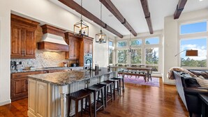 A spacious kitchen with a large island, wooden cabinets, and a stone backsplash. - Private Luxury Lodge in Colorado Forest (Colorado Springs)
