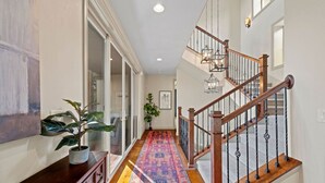 A hallway with a wooden staircase, a colorful rug, and a potted plant. - Private Luxury Lodge in Colorado Forest (Colorado Springs)