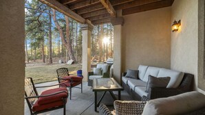 A covered outdoor seating area with wicker furniture, a table, and a sofa. - Private Luxury Lodge in Colorado Forest (Colorado Springs)