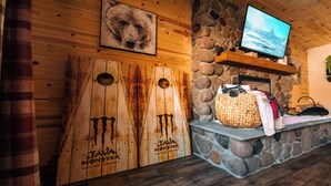 A rustic interior with wooden walls, a stone fireplace, a television, and a sign for Java Monster coffee energy.