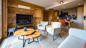Un salon moderne avec un mur d’accent en bois, un téléviseur, une table basse en bois et des sièges.