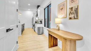 A modern kitchen with white cabinets, a wooden countertop, and a coffee machine.