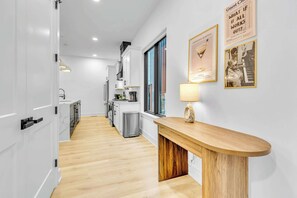 Une cuisine moderne avec des meubles blancs, un plan de travail en bois et une machine à café.