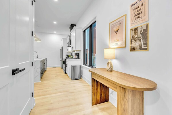 A modern kitchen with white cabinets, a wooden countertop, and a coffee machine.