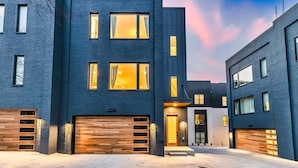 A modern two-story building with a dark facade, large windows, and a garage with wooden garage doors.