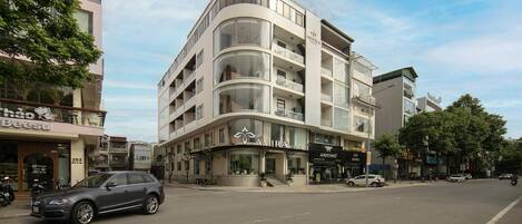 A modern hotel with a curved facade, multiple balconies, and a ground-level restaurant.