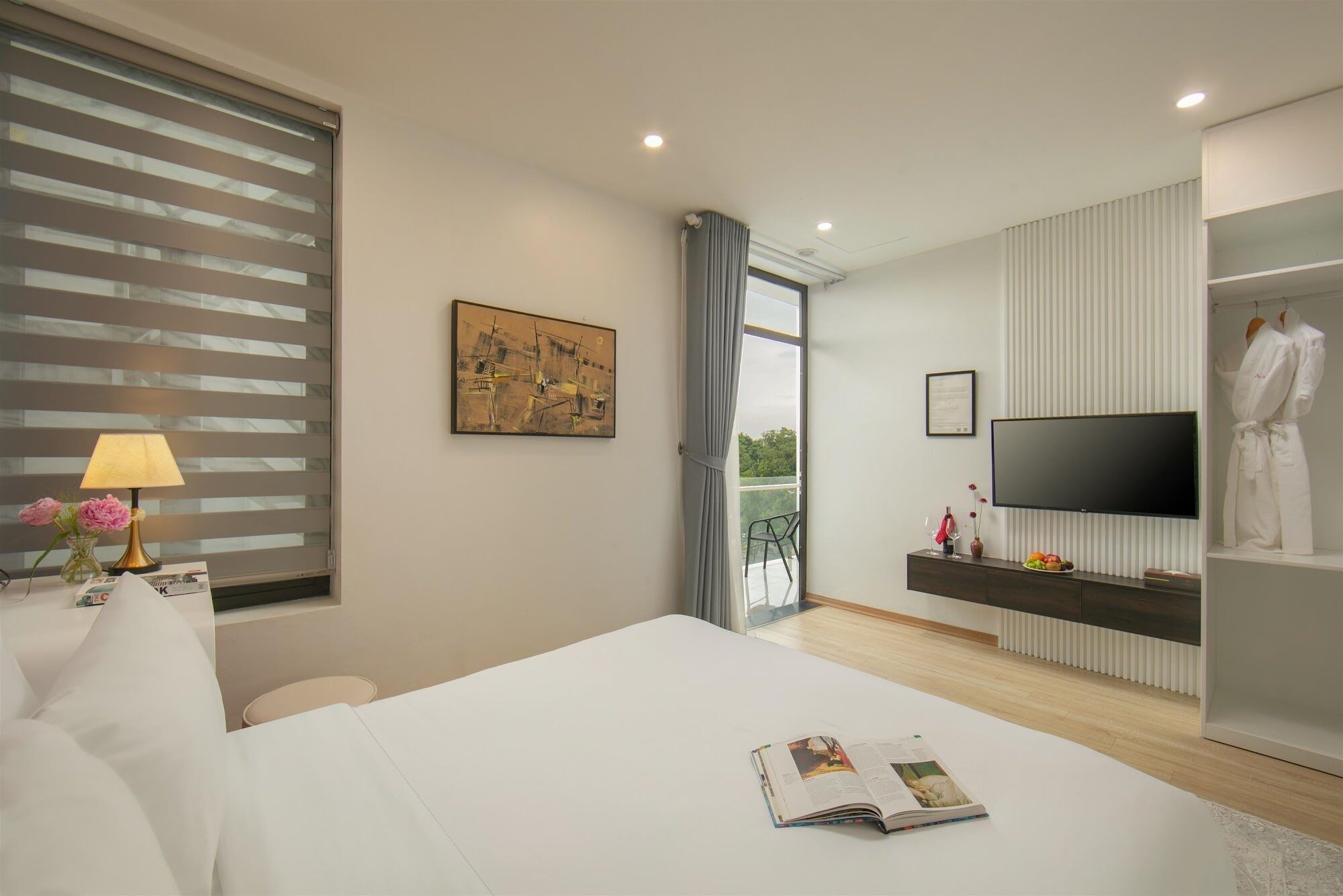 Une chambre d’hôtel moderne dotée d’un grand lit, d’un téléviseur à écran plat, d’une table de chevet avec une lampe, d’un tableau au mur et offrant une vue sur l’extérieur par une fenêtre.