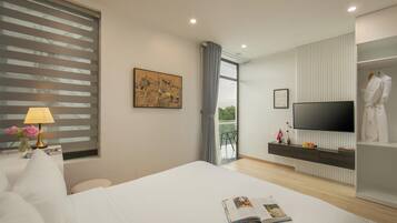 A modern hotel room with a large bed, a flat-screen TV, a bedside table with a lamp, a painting on the wall, and a view of the outdoors through a window.