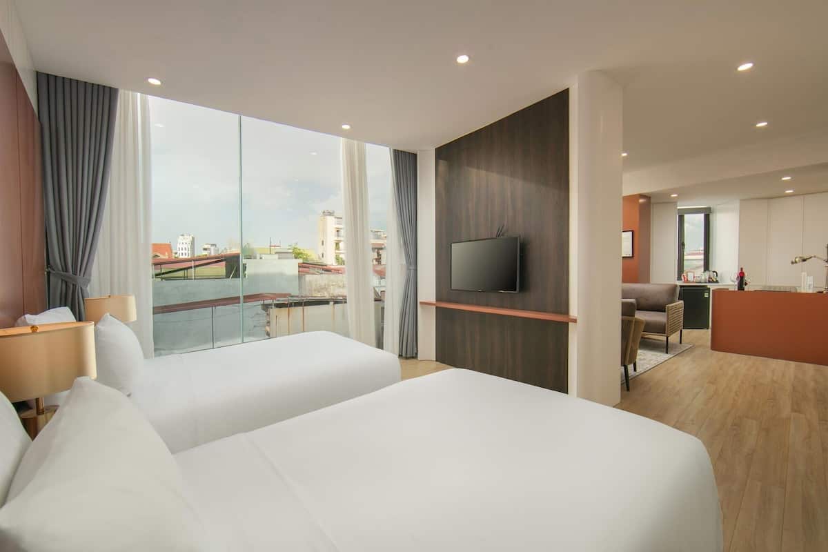 Une chambre d’hôtel moderne avec deux lits, une télévision, un bureau et une vue sur la ville.