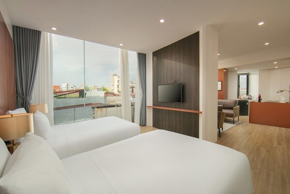 Una habitación de hotel moderna con dos camas, televisión, escritorio y vista a la ciudad.